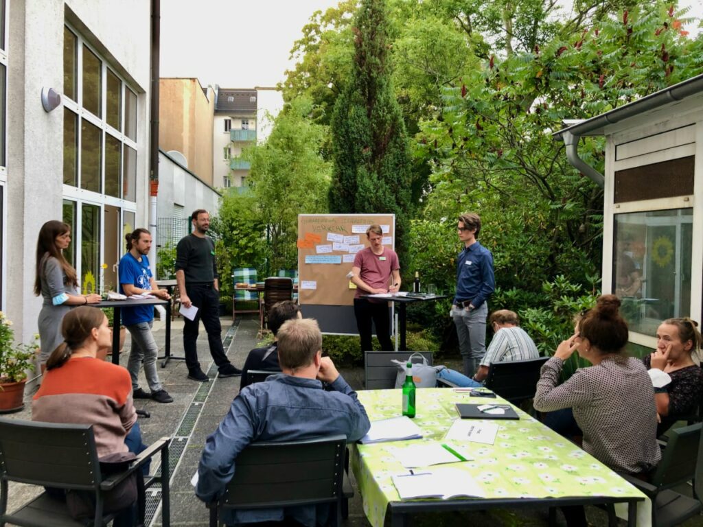 Verschiedene Personen stehen vor FlipChart und diskutieren umweltpolitische Themen.