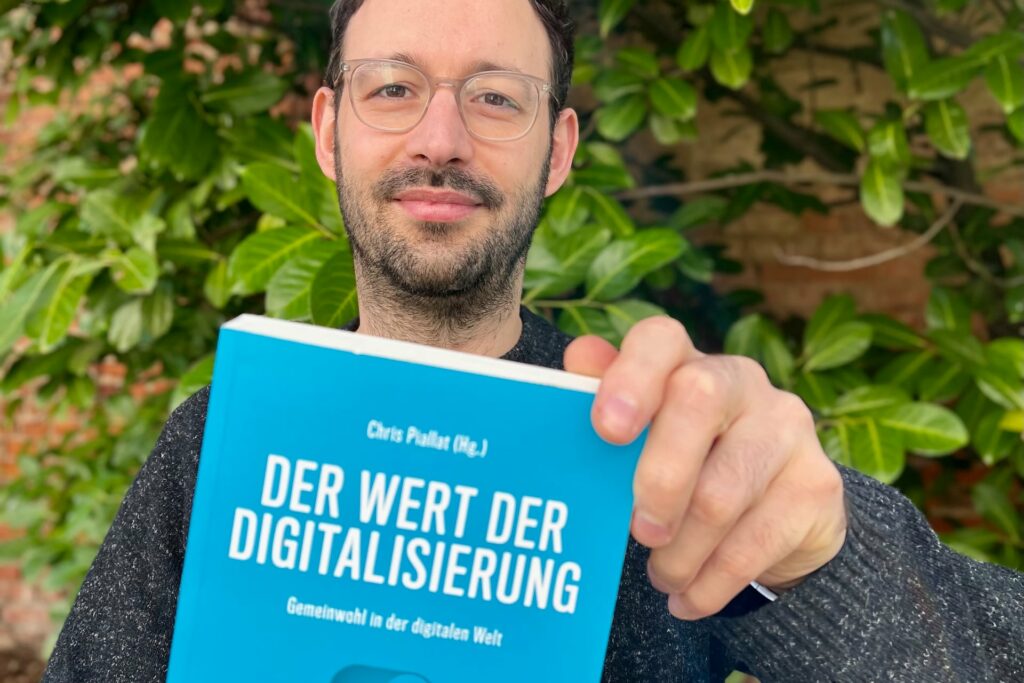 Portrait von Daniel auf dem er das Buch „Der Wert der Digitalisierung“ vor sich in die Kamera hält