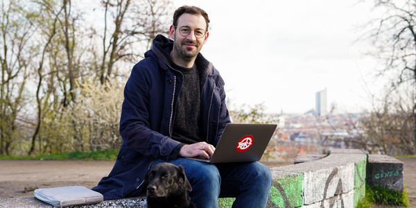 Daniel mit Laptop auf dem Schoß auf dem Fockeberg.