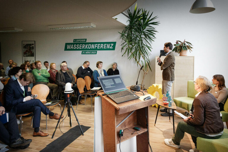 Dr. Marx und Gesa Steeger sind auf dem Podium zu sehen. Im Hintergrund ist die Aufschrift "1. Leipziger Wasserkonferenz" zu sehen.