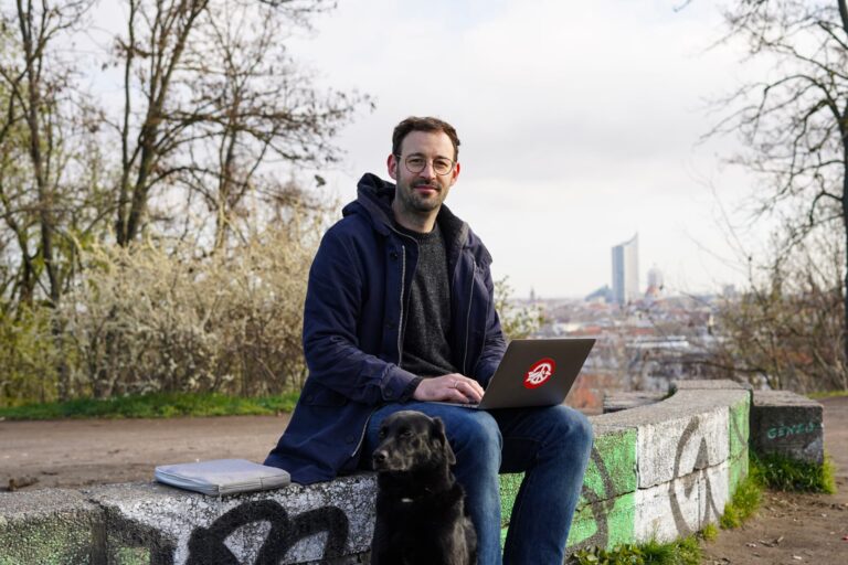 Daniel mit Laptop auf dem Schoß auf dem Fockeberg in Leipzig.